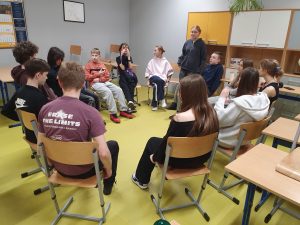 Uczniowie siedzą w kręgu w klasie i rozmawiają podczas szkolnych obchodów Dnia Kobiet.