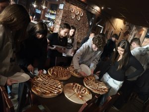 Ósmoklasiści realizują voucher i wspólnie jedzą pizzę po zakończeniu wizyty.