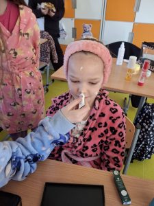 Uczennice w klasie nakładają krem na twarz koleżanki w trakcie szkolnych zabaw spa z okazji Dnia Kobiet.