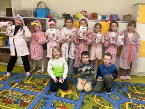 Grupa uczniów w klasie prezentuje otrzymane upominki podczas szkolnych obchodów Dnia Kobiet.