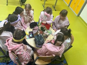 Uczennice siedzą przy stole w klasie i wykonują makijaż oraz zabiegi pielęgnacyjne podczas szkolnego dnia spa.