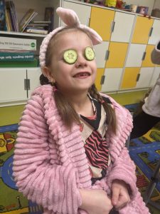 Dziewczynka w klasie podczas szkolnego spa – na oczach ma plasterki ogórka i opaskę kosmetyczną.