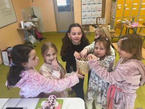 Grupa uczennic w klasie częstuje się popcornem podczas wspólnego świętowania Dnia Kobiet.