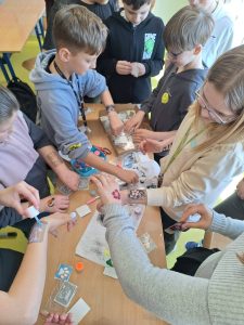 Uczniowie wykonują tymczasowe tatuaże przy szkolnym stoliku podczas obchodów Dnia Kobiet.