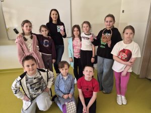 Nauczycielka i uczniowie pozują razem do zdjęcia w klasie podczas świętowania Dnia Kobiet.