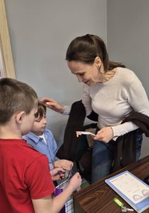 Uczniowie wręczają nauczycielce drobny upominek z okazji Dnia Kobiet.