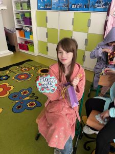 Uczennica siedzi w klasie i prezentuje otrzymany upominek z okazji Dnia Kobiet.