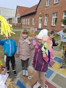 Dzieci trzymają kolorowe kukły ze słomy i papieru, przygotowane na tradycyjne pożegnanie zimy.
