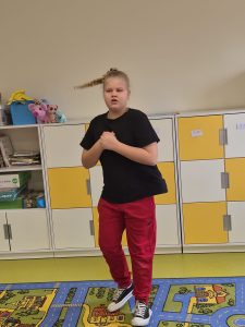 Uczennica klas 1–3 prezentuje swoje hobby taneczne, wykonując układ ruchowy w sali lekcyjnej.