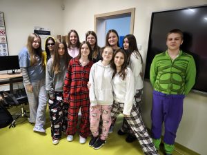 Grupa uczniów w piżamach stoi w klasie i pozuje do zdjęcia podczas szkolnych obchodów Pierwszego Dnia Wiosny – Dnia w Piżamie.