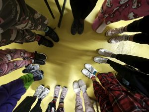 Uczniowie stoją w kręgu, pokazując różne, kolorowe skarpetki i buty jako symbol solidarności ze Światowym Dniem Downa.