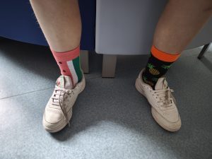 Zbliżenie na dwie różne, kolorowe skarpetki założone do butów – symbol obchodów Światowego Dnia Downa.