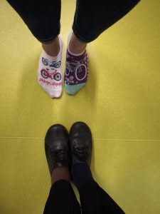 Dwie osoby stoją naprzeciw siebie, pokazując niepasujące, kolorowe skarpetki jako znak solidarności ze Światowym Dniem Downa.