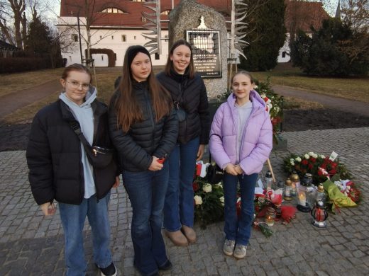 Uczennice Samorządu Uczniowskiego stoją przy pomniku Ofiar Wyklętych po złożeniu kwiatów i zapaleniu zniczy w dniu 1 marca.