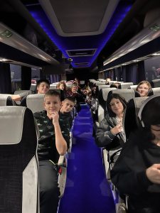 Uczniowie siedzą w autokarze podczas wyjazdu edukacyjnego, patrzą w stronę aparatu.