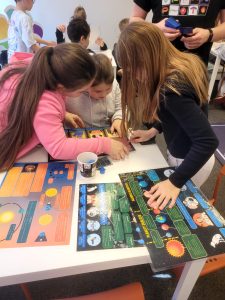 Uczniowie pracują w grupie nad edukacyjną grą planszową o tematyce kosmicznej.