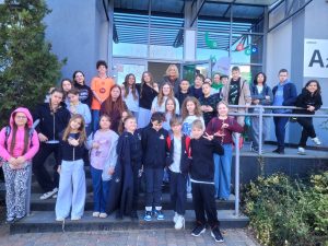 Grupa uczniów i nauczycieli pozuje do zdjęcia przed wejściem do Laboratorium Wyobraźni.