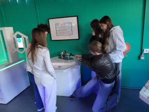 Uczniowie wykonują doświadczenie z półkulami magdeburskimi, próbując rozdzielić połączone elementy.