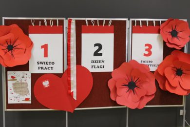 Tablica dekoracyjna z napisami „1 Święto Pracy”, „2 Dzień Flagi”, „3 Święto Konstytucji” ozdobiona czerwonymi makami.