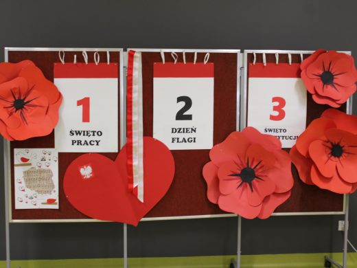 Tablica dekoracyjna z napisami „1 Święto Pracy”, „2 Dzień Flagi”, „3 Święto Konstytucji” ozdobiona czerwonymi makami.