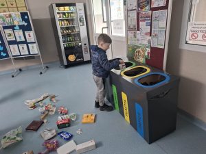 Dziecko wrzuca odpady do pojemnika do segregacji śmieci, ucząc się zasad recyklingu.