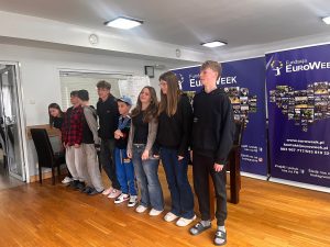 Grupa uczniów stoi w rzędzie na scenie w trakcie prezentacji podczas obozu EuroWeek.