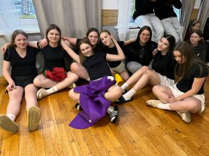 Grupa uczennic siedzi razem na podłodze i odpoczywa w trakcie przerwy podczas obozu.