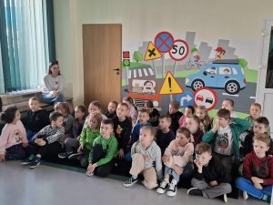 Grupa dzieci siedzi na podłodze sali edukacyjnej WORD i uczestniczy w zajęciach o bezpieczeństwie drogowym.