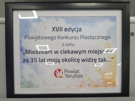 Plansza informacyjna XVI Powiatowego Konkursu Plastycznego z tytułem wydarzenia i logotypem Powiatu Toruńskiego.