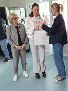 Nauczycielka wręcza uczennicy nagrodę i dyplom w szkolnym konkursie literackim.