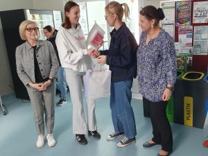 Laureatka konkursu literackiego odbiera nagrodę i ściska dłoń nauczycielki.