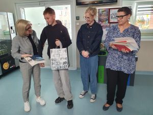 Uczeń odbiera książkę i upominek za udział w szkolnym konkursie literackim.