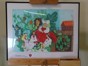 Kolorowa ilustracja przedstawiająca rodzinę i dzieci w stylizowanych strojach siedzących pośród dużych liści i czerwonych owoców. W tle widoczny jest budynek oraz element przypominający zegar. Praca utrzymana jest w żywych odcieniach zieleni i czerwieni.