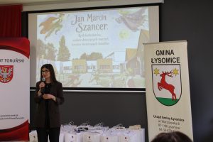 Przemówienie organizatorki wydarzenia podczas podsumowania Wojewódzkiego Konkursu Plastyczno-Recytatorskiego poświęconego Janowi Marcinowi Szancerowi.