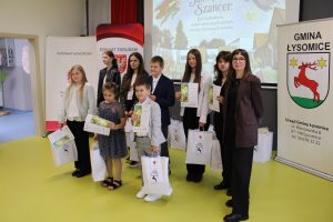 Laureaci jednej z kategorii konkursowych pozują do pamiątkowego zdjęcia z dyplomami i torbami z nagrodami. Obok stoją przedstawiciele organizatorów gali.
