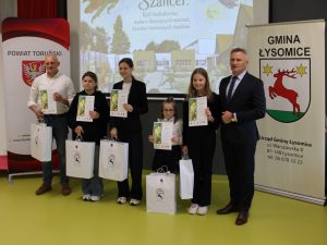 Laureaci konkursu pozują z dyplomami i nagrodami razem z przedstawicielami organizatorów wydarzenia.