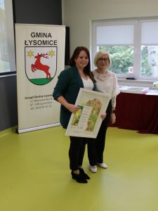 Wręczenie podziękowania dla osoby współorganizującej wydarzenie. Uczestniczki prezentują oprawioną pracę konkursową.