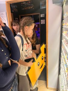 Uczniowie oglądają ekspozycję zbudowaną z klocków LEGO w muzeum. Na pierwszym planie widoczna jest gablota z kolekcją figurek.