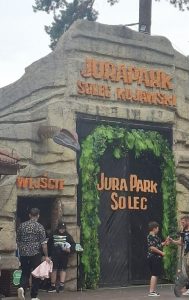 Brama wejściowa do JuraParku w Solcu Kujawskim z napisem „JuraPark Solec Kujawski”. Przed wejściem znajdują się odwiedzający.