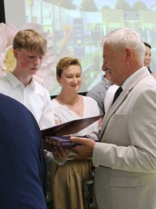Absolwent szkoły podstawowej w Ostaszewie odbiera pamiątkowy dyplom i nagrodę książkową podczas Gali Absolwentów Gminy Łysomice.