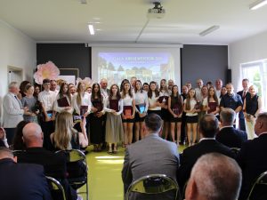 Absolwenci szkoły podstawowej w Ostaszewie wraz z rodzicami i przedstawicielami samorządu pozują do wspólnego zdjęcia podczas Gali Absolwentów Gminy Łysomice.