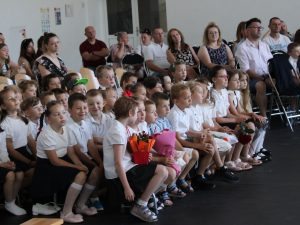 Uczniowie klas I–III oraz rodzice siedzą na widowni i obserwują występy przygotowane z okazji zakończenia roku szkolnego.