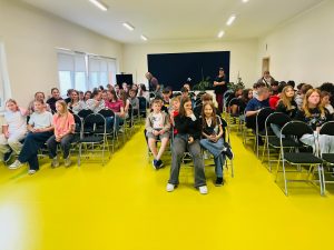 Uczniowie zajmują miejsca w sali konferencyjnej przed prelekcją dotyczącą stresu i sposobów radzenia sobie z nim. Młodzież oczekuje na rozpoczęcie spotkania.