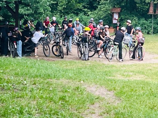 Duża grupa uczniów zgromadzona z rowerami przy wiacie na Barbarce. Uczestnicy kończą odpoczynek i przygotowują się do dalszej części rowerowej wyprawy w ramach akcji „Rowerowa Stolica Polski”.