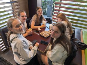 Uczennice siedzą przy stoliku w restauracji podczas postoju w Toruniu. Korzystają z chwili odpoczynku przed dalszą częścią rowerowej wyprawy.