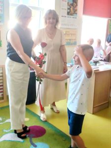 Chłopiec wręcza kwiat pani dyrektor podczas podziękowań składanych wychowawczyni i dyrekcji na zakończenie edukacji przedszkolnej.