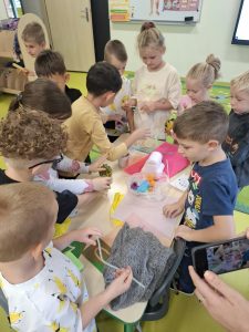 Dzieci wspólnie badają przygotowane materiały, dotykając przedmiotów o różnych fakturach i porównując swoje odczucia.