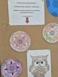 Wystawa prac z okazji Dnia Kropki – kolorowe, okrągłe wzory geometryczne i rysunek sowy ozdobionej kropkami. Nad pracami znajduje się zachęta do wybrania i pokolorowania własnej „kropki”.