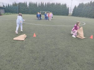 Uczennice uczestniczą w konkurencji z workami podczas jesiennych zabaw sportowych na boisku.