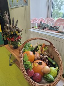 Kosz wypełniony dyniami, cukiniami, jabłkami, cebulą, orzechami i innymi jesiennymi darami natury.